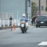 道路上で前の車を取り締まる白バイの交通違反取締活動の写真