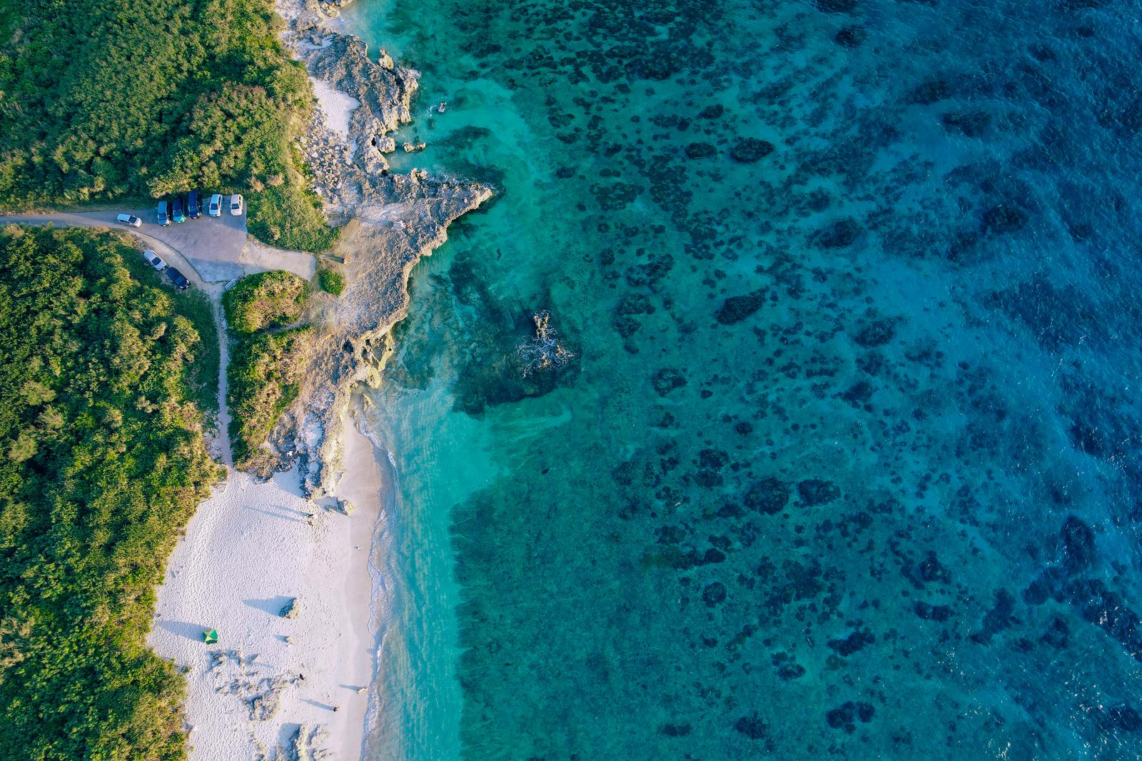 緑の森と白い砂浜に囲まれた透明度の高い宮古ブルーの海を空撮した風景