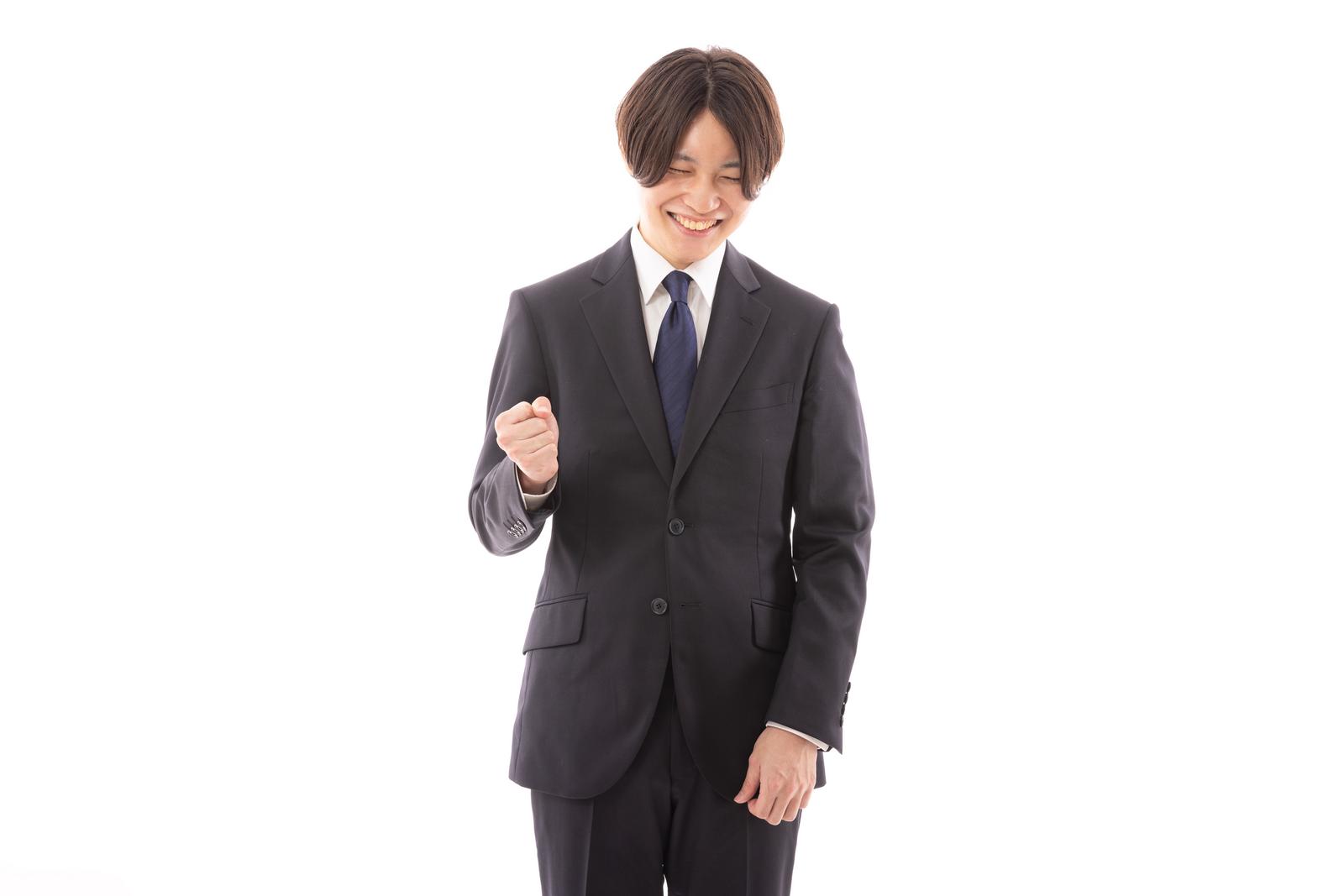 黒いスーツを着た男性がガッツポーズで喜ぶ［モデル：SHUN］