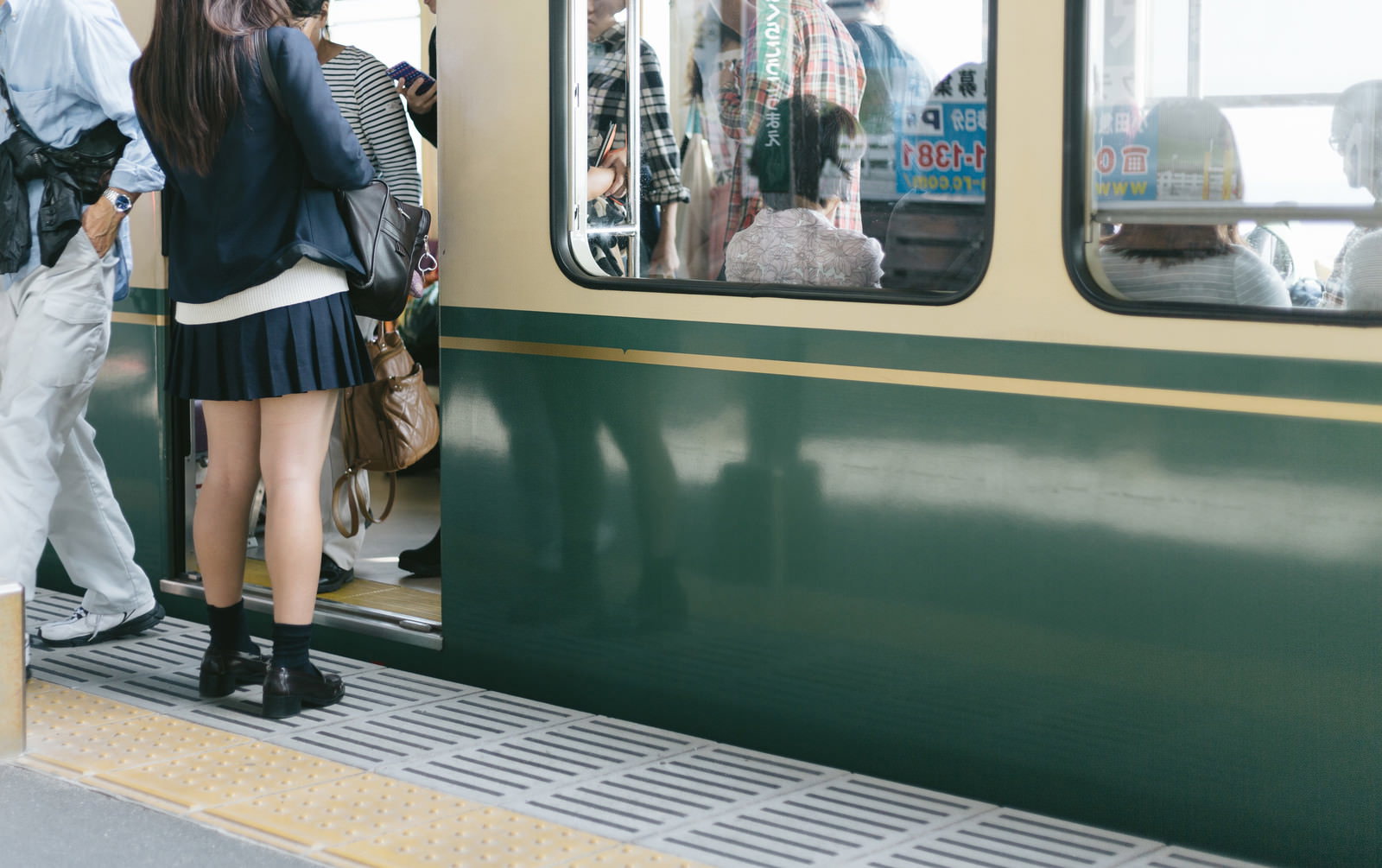 High school girl in uniform waiting on Enoden platform