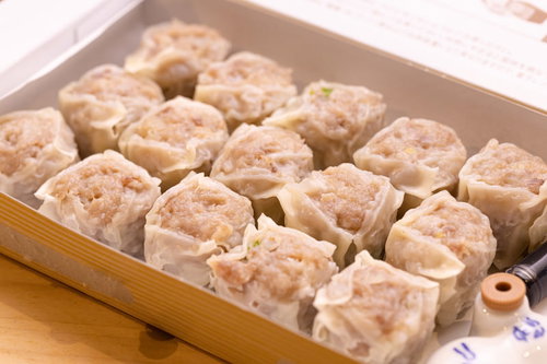 白い箱に15個並んだ焼売（シウマイ）の蒸し物
