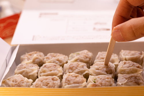 箱に並んだシウマイを手で取ろうとする瞬間