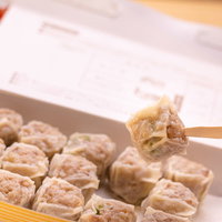 大好物の一口焼売（シウマイ）を箸でつまむの写真