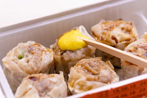 シウマイに黄色いからしをつける木の箸と中華料理の定番