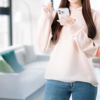 スマホで部屋探しをする笑顔の女性とリラックス空間の写真