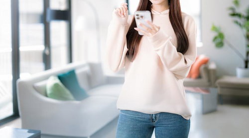 スマホで部屋探しをする笑顔の女性とリラックス空間の写真