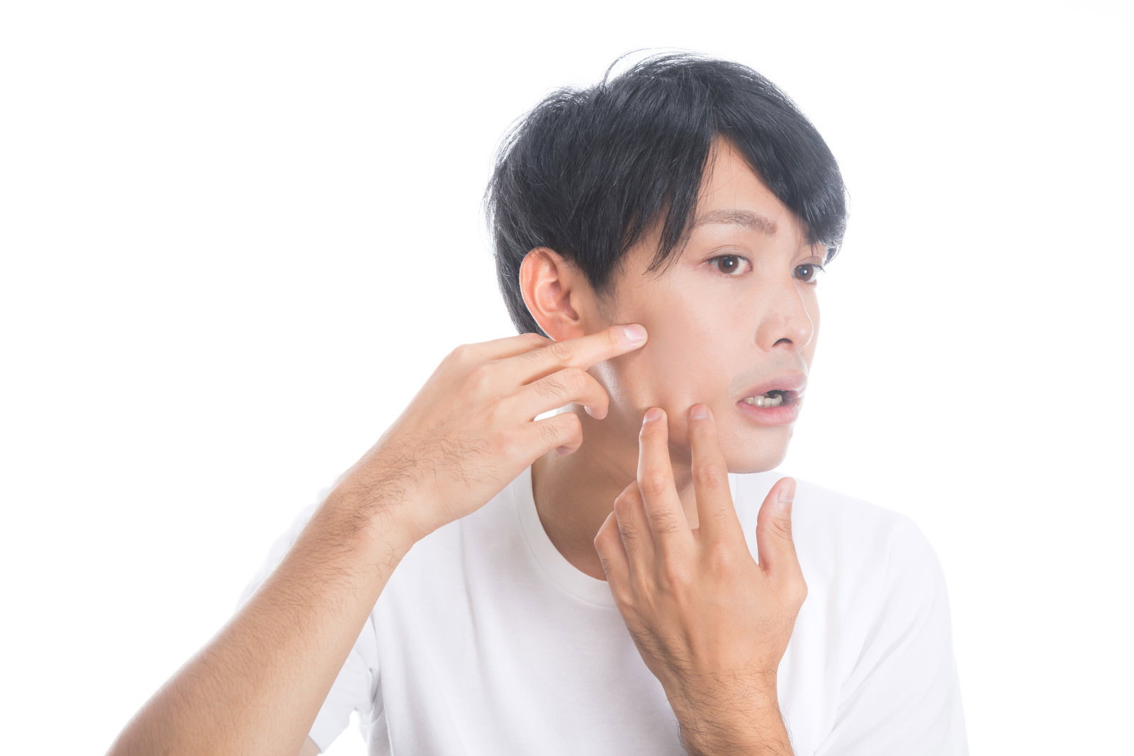 白いTシャツを着た男性が頬に手を当ててニキビを気にしている様子［モデル：完伍］