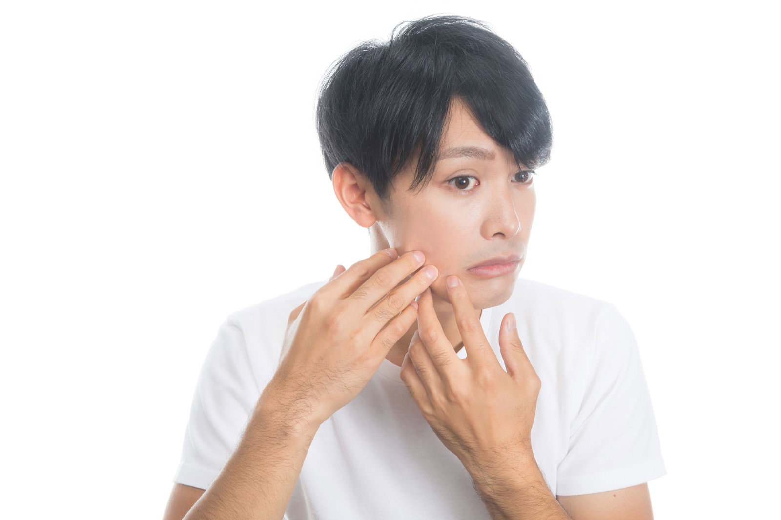 白いTシャツを着た男性が両手で頬に触れて肌の状態を確認している［モデル：完伍］