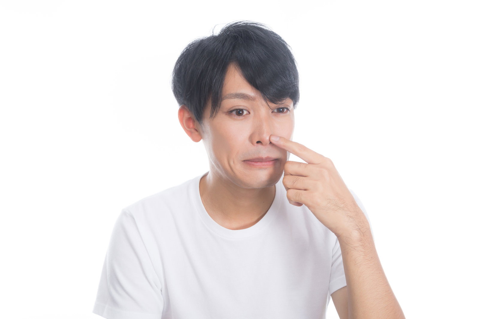 鼻頭の吹き出物を気にして指を当てる白いTシャツの男性［モデル：完伍］