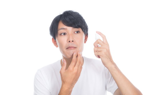ひげ剃りあとに肌ケアするあごの状態をチェックする男性