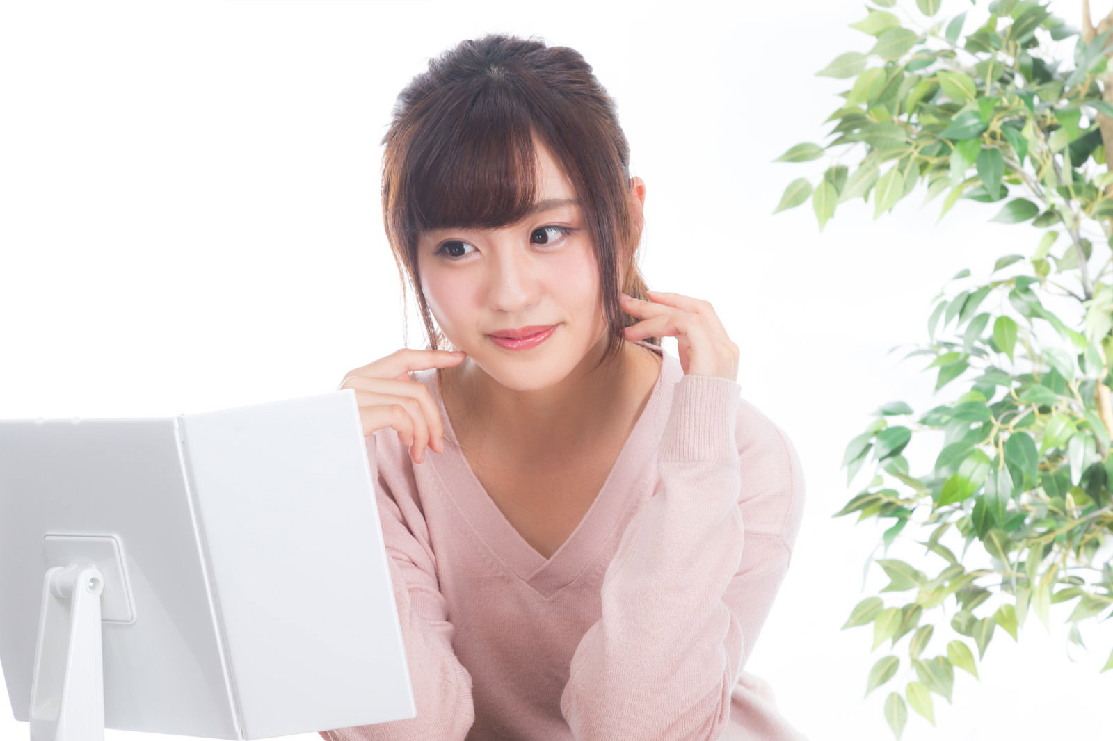 鏡を見ながら頬に手を添えて肌の調子を確認している笑顔の女性［モデル：河村友歌］