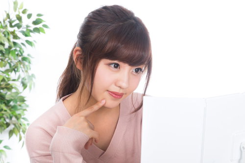 鏡を見ながら肌の状態を確認するスキンケアケアをする若い女性