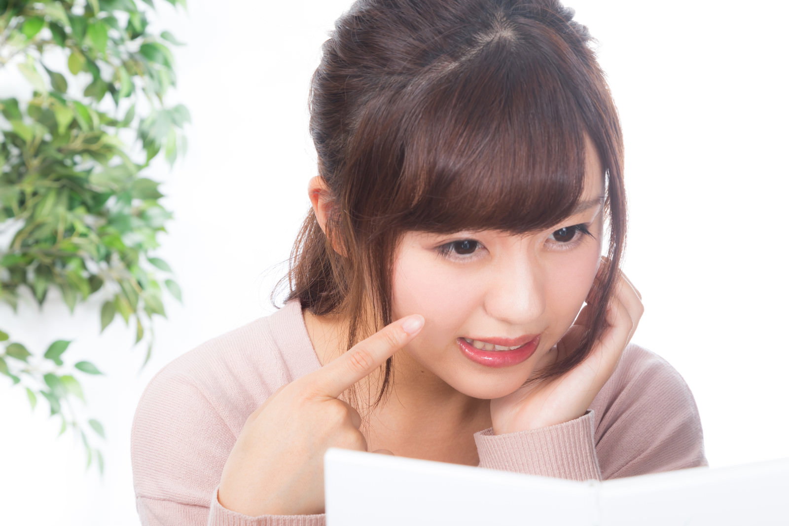鏡を見ながら頬に手を当て困った表情を見せる女性［モデル：河村友歌］