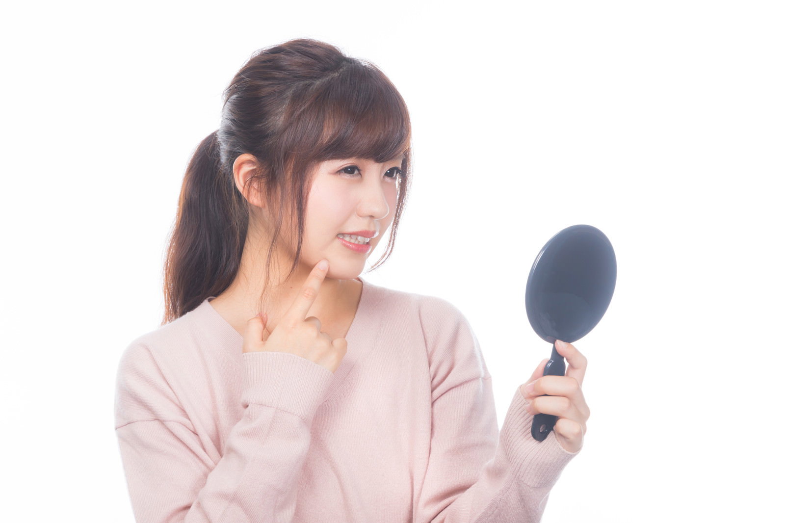 手鏡を持って肌の状態をチェックしている白いトップスの女性［モデル：河村友歌］