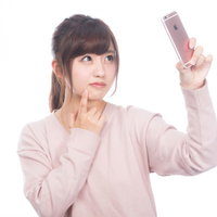 手鏡のかわりにスマホの内向きカメラで肌をチェックする女性の写真