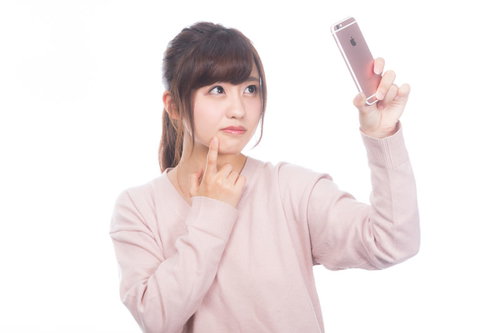 手鏡のかわりにスマホの内向きカメラで肌をチェックする女性