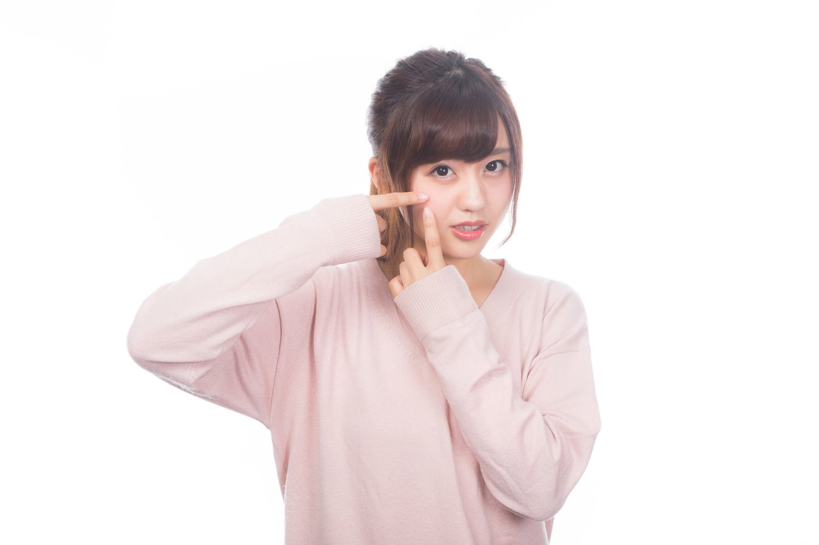 頬に手を当ててニキビを気にする困った表情のピンクの服を着た女性［モデル：河村友歌］