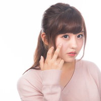顔の肌荒れを気にする若い女性のスキンケアの写真