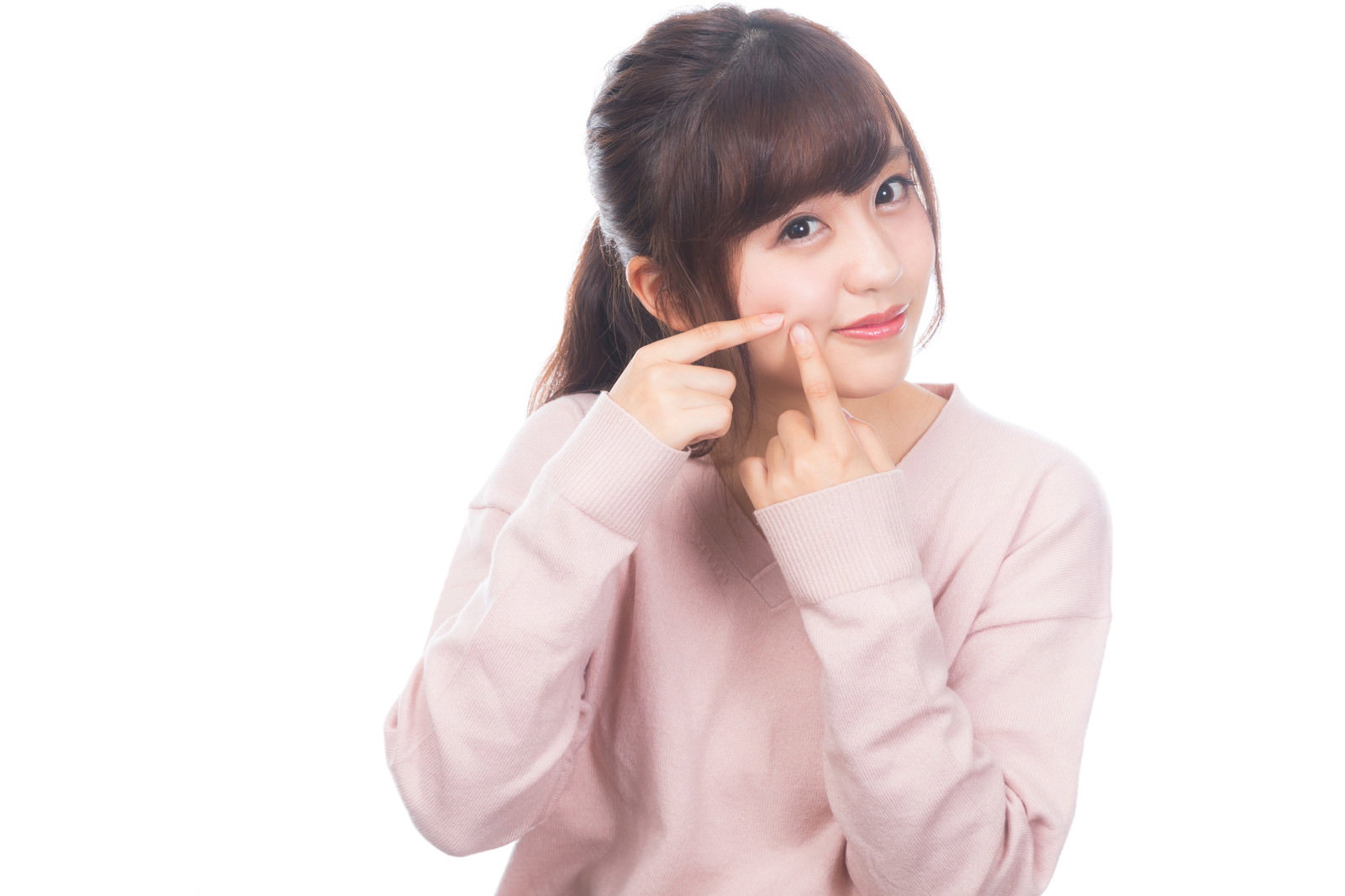 淡いピンクのトップスを着た女性が右手を頬に当てて微笑んでいる［モデル：河村友歌］