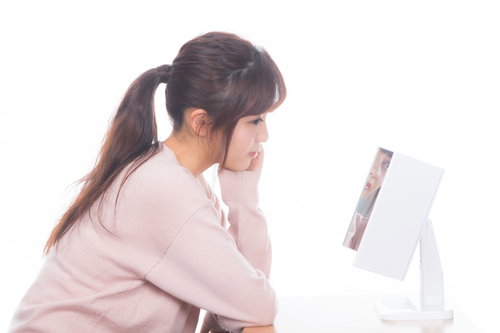 洗面台の鏡の前でスキンケアをする美肌にうっとり女子