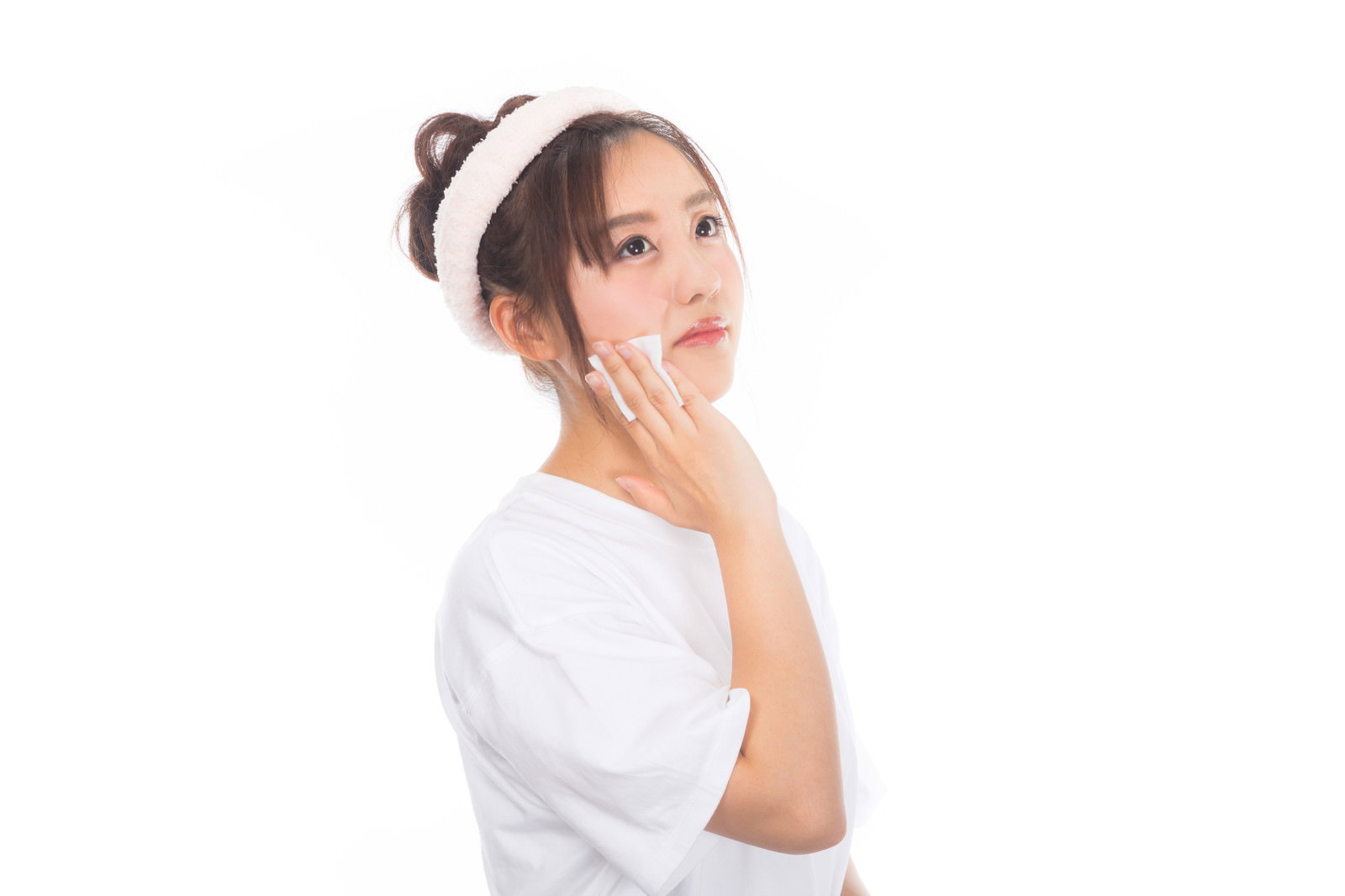 白いタオルを頭に巻いた女性がコットンでメイクを落としている［モデル：河村友歌］