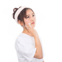 白いタオルを頭に巻いてコットンでメイクを落とす女性の写真