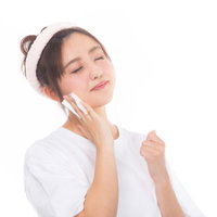 白いコットンで目を瞑りながらメイクを落とす女性の写真