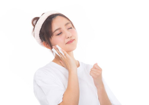 白いコットンで目を瞑りながらメイクを落とす女性