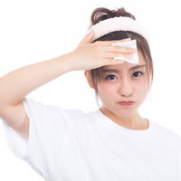 コットンで額のメークを落とす女性のスキンケアの写真