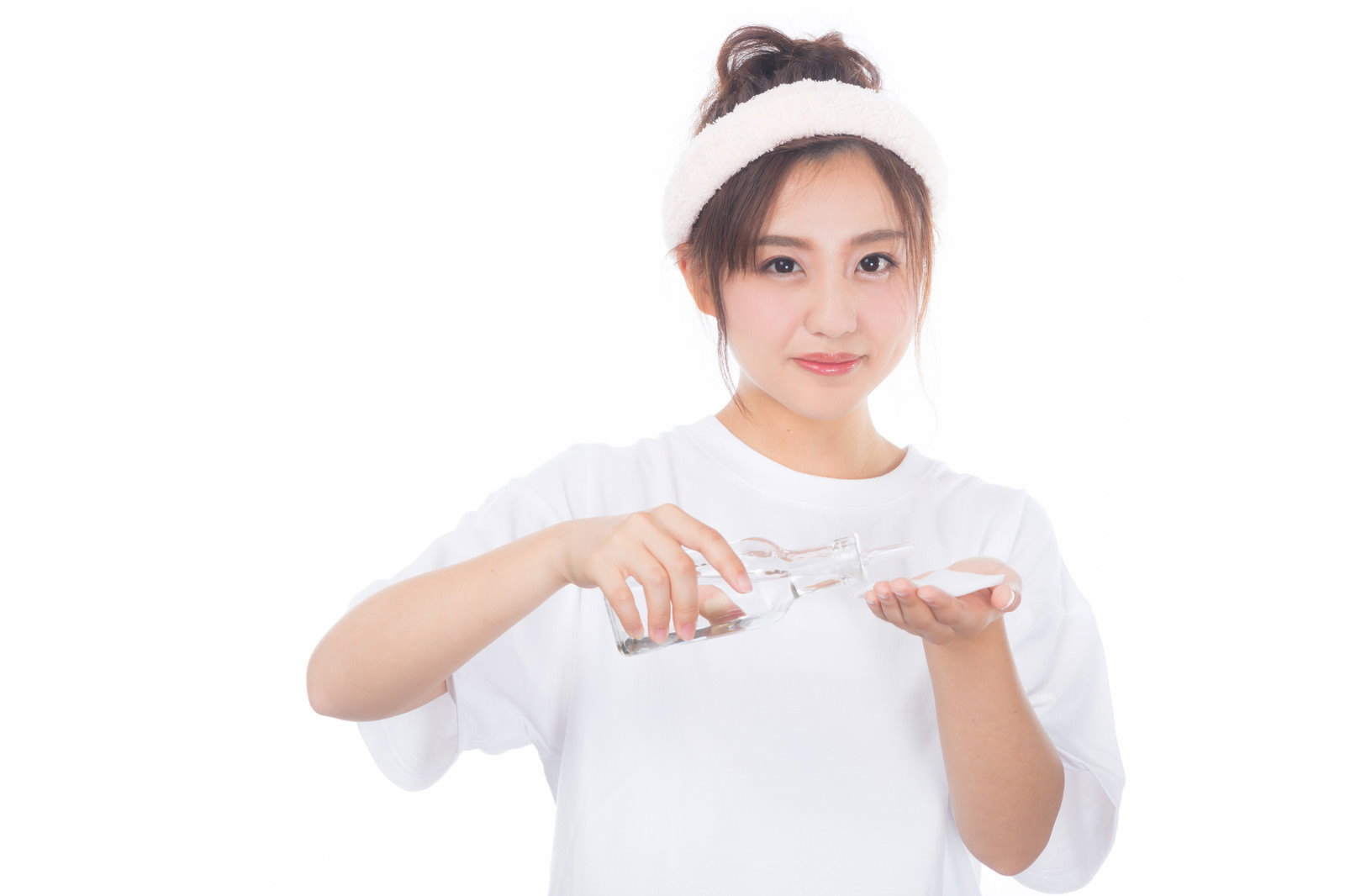 白い服を着た女性が透明な容器からコットンに美容液を垂らしている［モデル：河村友歌］