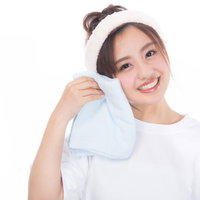 白いタオルを頬にあてるスキンケア中の女性の写真