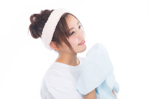 爽やかな朝にタオルを持って顔を洗う女性のスキンケア