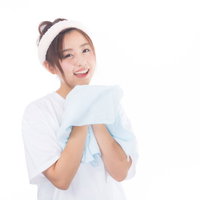 朝に顔を洗った後、白いタオルで顔を拭く女性の写真