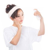 顔に霧吹きでミストを吹きかけるスキンケアする女性の写真