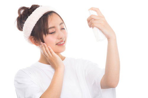 化粧水のミストで顔に潤いを与える女性のスキンケア