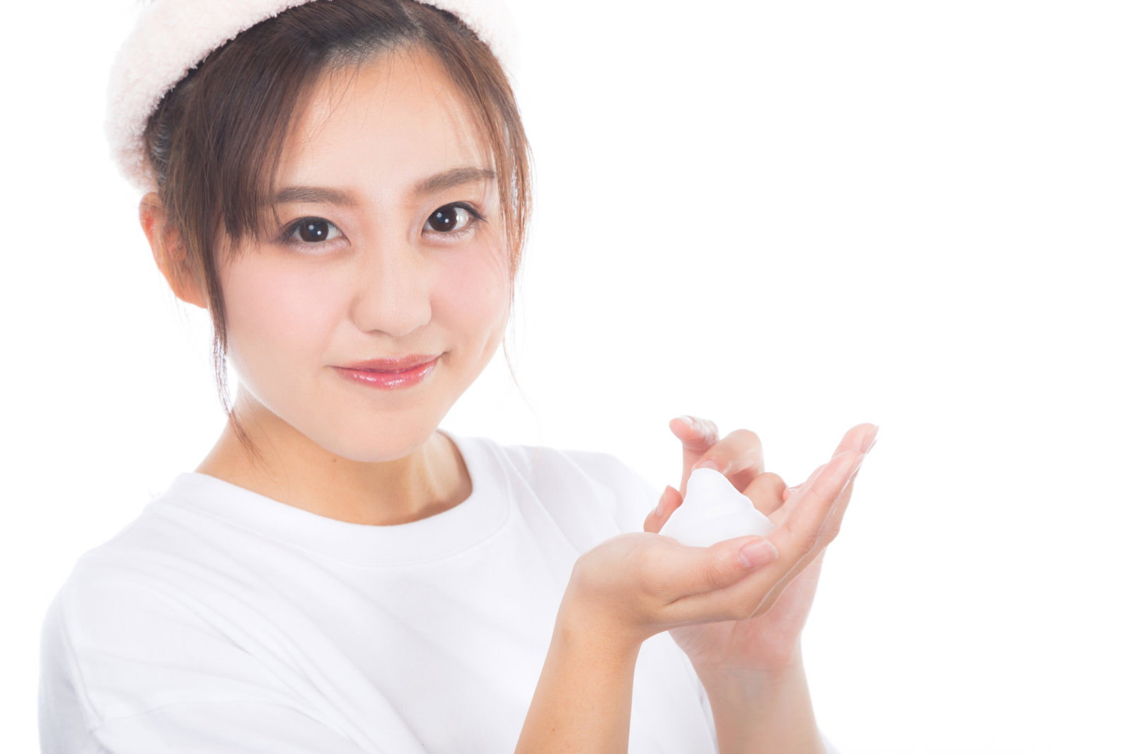白い服を着た女性が手のひらにクレンジングの白い泡を持っている［モデル：河村友歌］