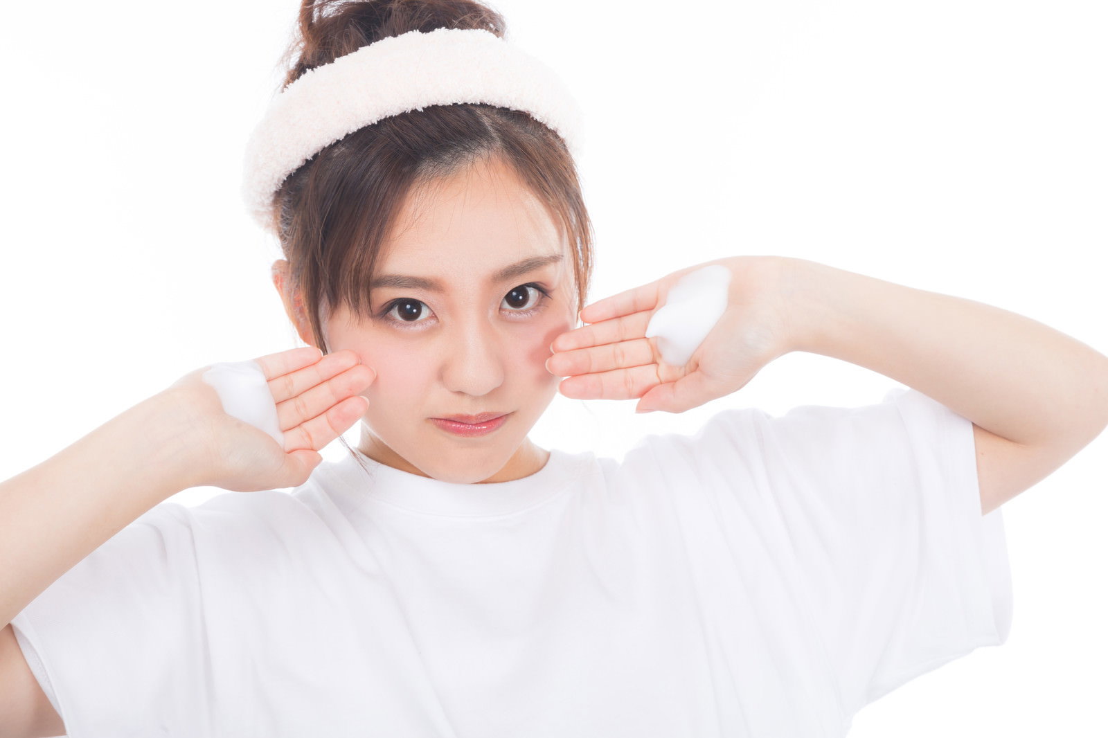 両手にクレンジングの泡を持ち、白い衣装を着た女性［モデル：河村友歌］