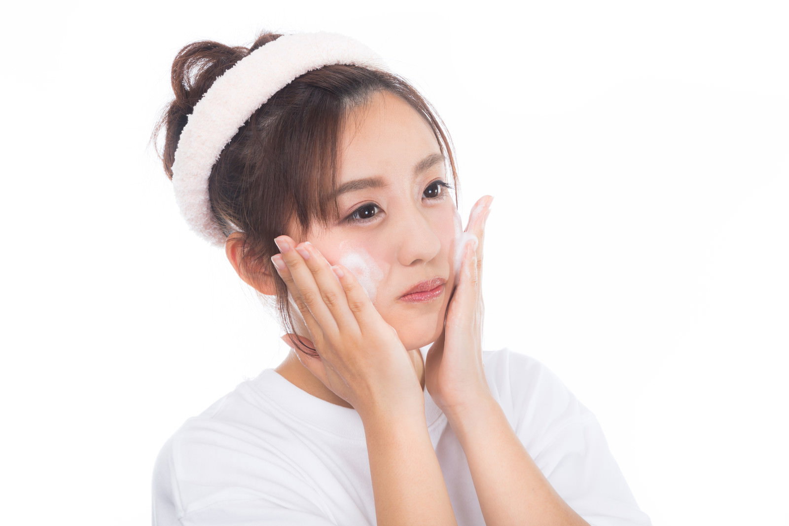 白いトップスを着た女性がクレンジングの泡で洗顔している様子［モデル：河村友歌］
