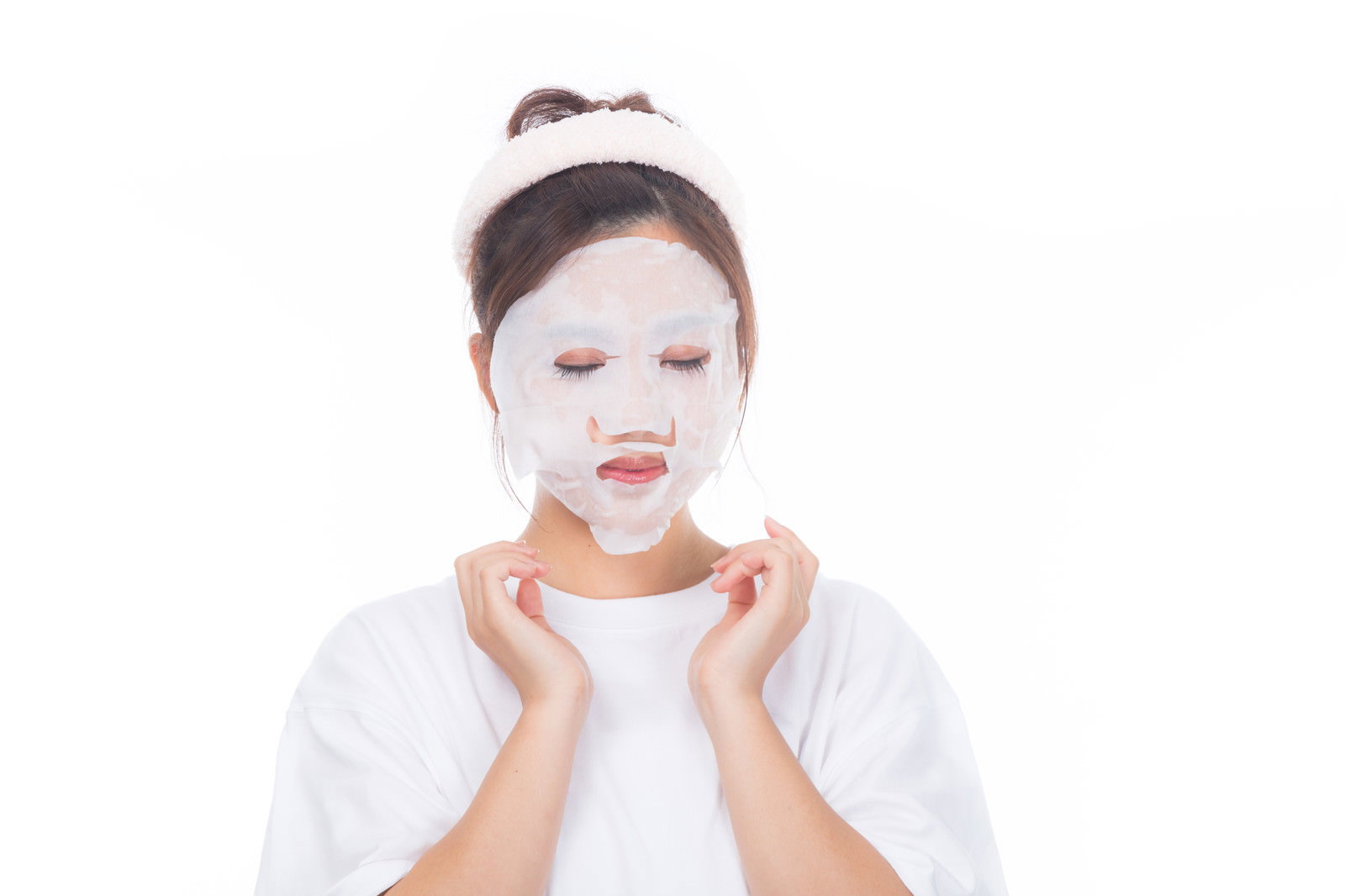 白いフェイスパックをつけて両手で顔を包む女性［モデル：河村友歌］