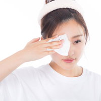 白いコットンで目元の化粧を落とす若い女性の写真