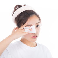 白いコットンで目のまわりのメイクを落とす女性の写真