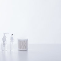 透明な美容液のボトルと白い綿棒のスキンケア用品の写真