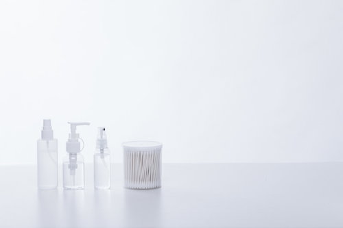 透明な美容液のボトルと白い綿棒のスキンケア用品