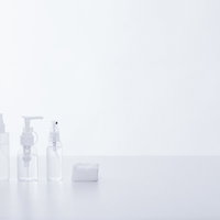 透明な詰め替え用化粧水ボトルとコットン、白い背景の写真