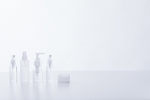 透明な詰め替え用化粧水ボトルとコットン、白い背景