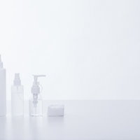 白い背景に並べた化粧水ボトルとコットン、スキンケア用品の写真