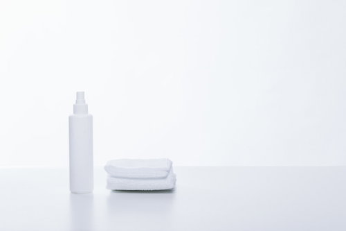 白い背景に並べたタオルと乳液ボトルのスキンケア用品