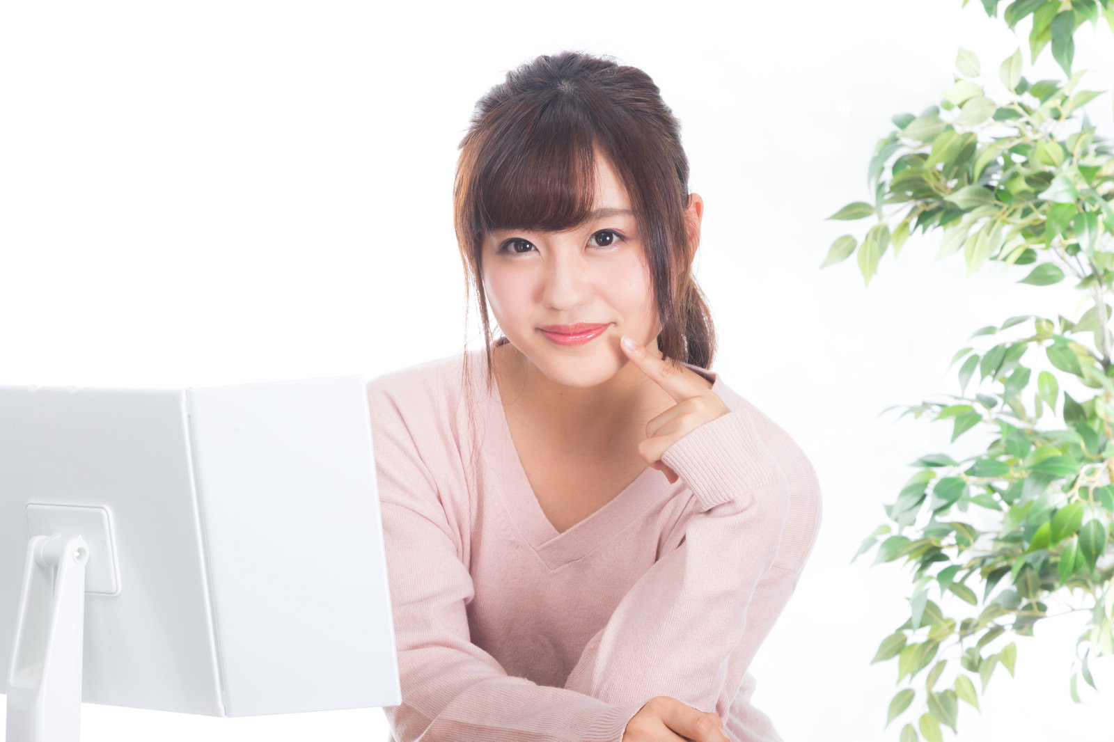 デスクで頬に手を当てて微笑む女性［モデル：河村友歌］