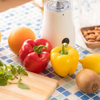 ジューサーとパプリカやキウイ、バジルなど新鮮な食材の写真