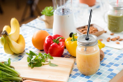 テーブルの上にあるスムージーと緑黄色野菜・果物